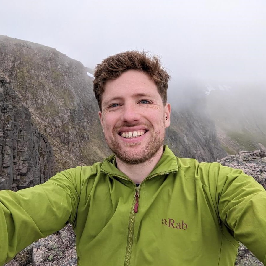 A selfie of Wil Treasure in a green top in the mountains